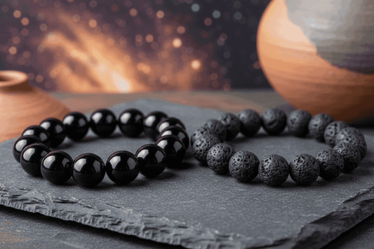 Two handcrafted energy bracelets, one polished black obsidian and one matte lava stone, on slate.