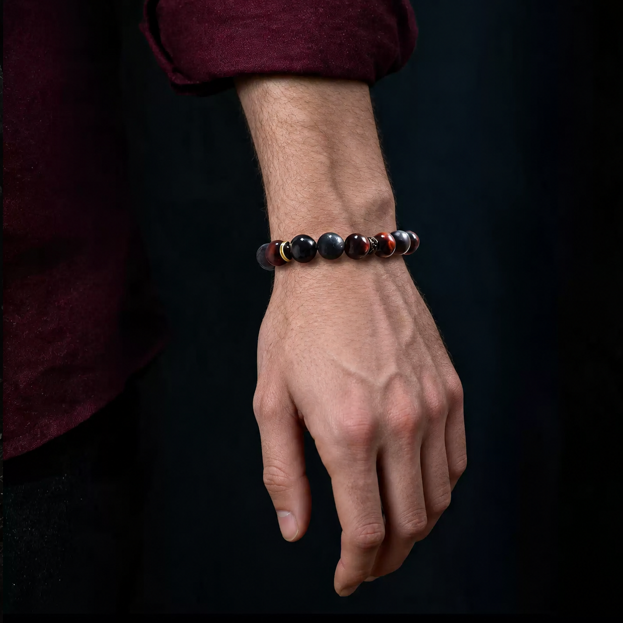 Red and black stone bracelet worn on the wrist with a dark burgundy sleeve