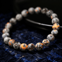 Close-up of a gray mottled flame stone bracelet with scattered orange UV-reactive areas