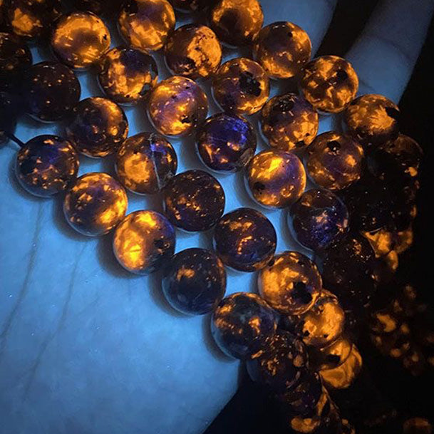 Multiple flame stone bracelets showing varied orange fluorescent patterns under UV light