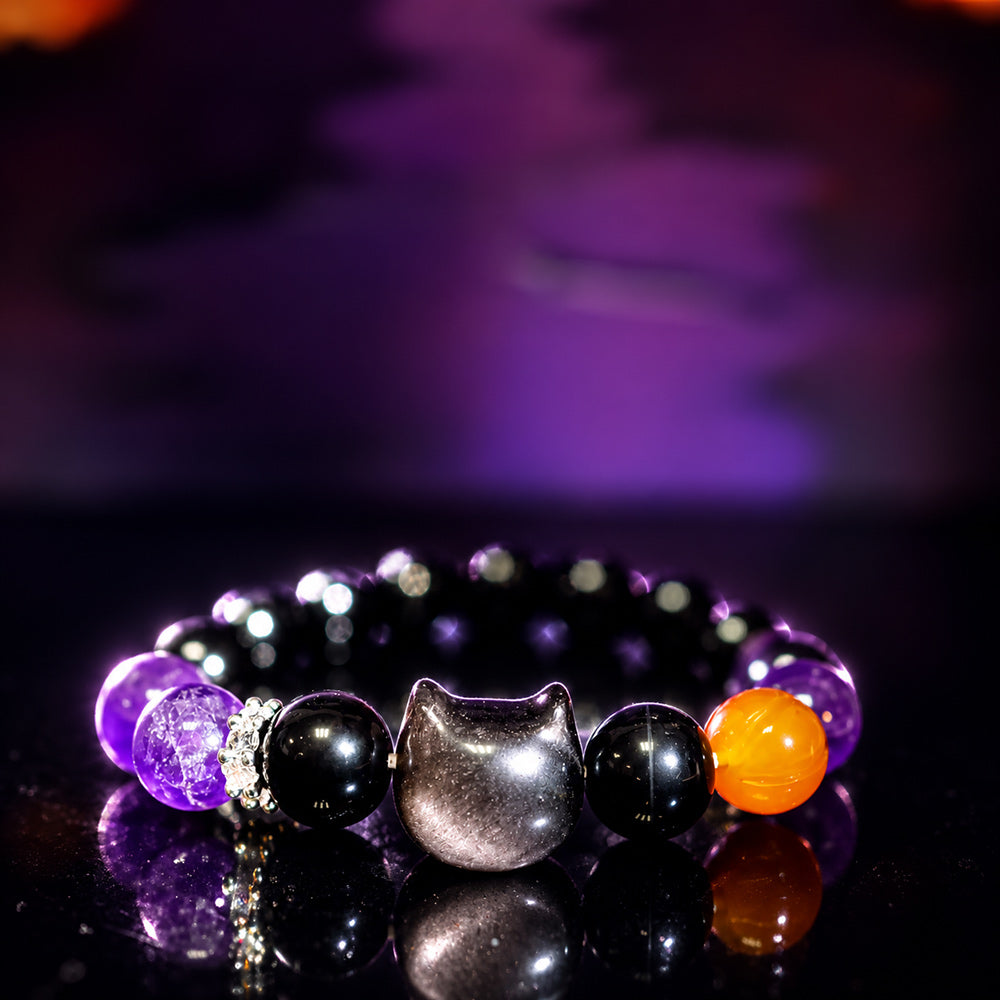 Close-up of the carved silver sheen obsidian cat centerpiece on a natural stone bracelet