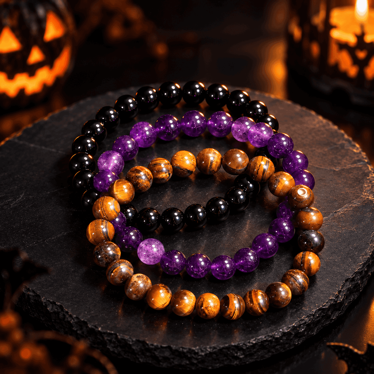 Obsidian, tiger’s-eye and amethyst bracelets arranged as a three-piece stack on a dark stone surface
