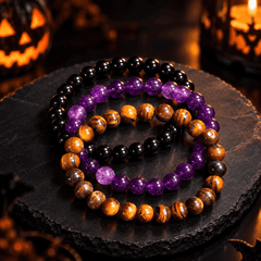 Obsidian, tiger’s-eye and amethyst bracelets arranged as a three-piece stack on a dark stone surface