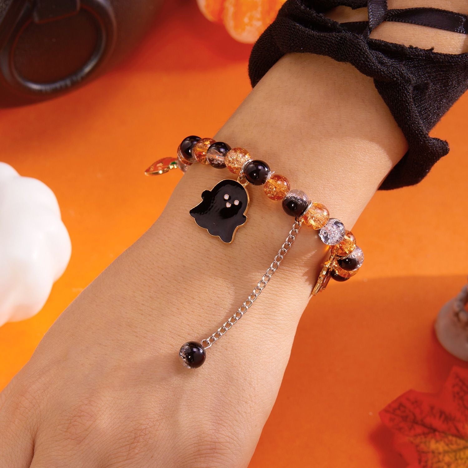 Pumpkin Boo orange and black ghost charm bracelet worn on the wrist